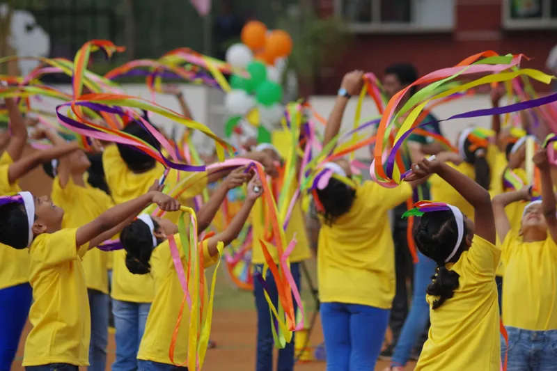 Children in yellow t-shirts taking part in a ribbon display at an NGO event in India
